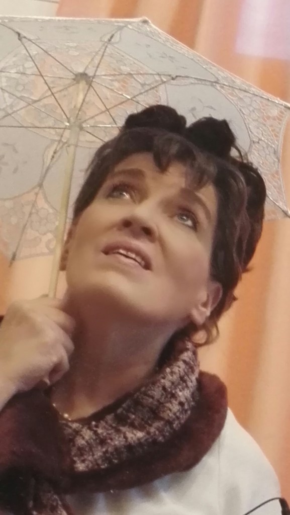 Alma katsoo ylös herkästi aurinkovarjo kädessään. (Tähtiin kirjoitettu -musiikkidraama)